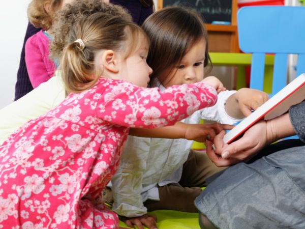 young children pointing at a book
